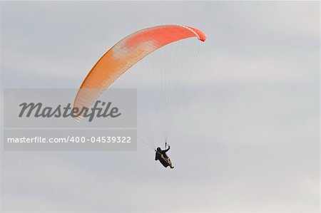A man with a colorful paraglider flying in the sky
