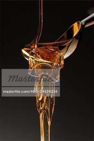 Golden color honey spilling over the spoon stock photo