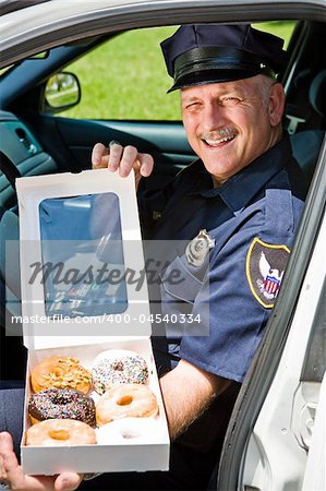 Police officer sitting in his squad car with a box of donuts.