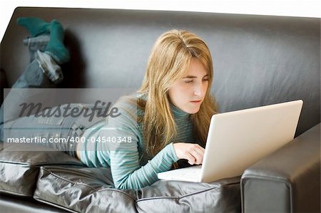 A young woman relaxing at home on her sofa with her laptop