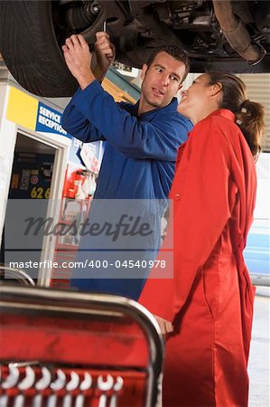 Two mechanics working under car smiling