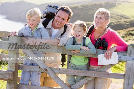 Family on cliffside path leaning on fence and smiling