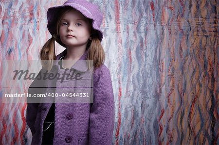 Gorgeous little fashion model posing in violet coat.