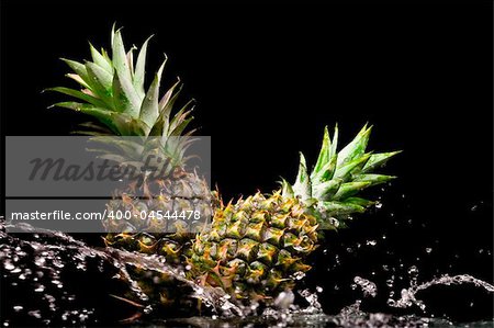 View of two fresh pineapples getting splashed with water