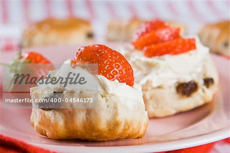 Scones, strawberries and clotted cream on a pink plate