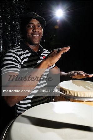 Portrait of young latino percusionist playing african drums