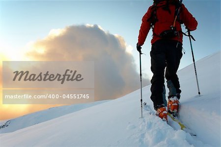 Backcountry skier walks in the snow at sunset, italian alps, europe.