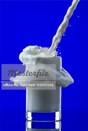 View of glass getting filled with milk on blue back