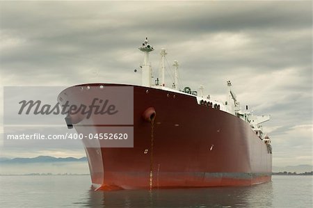 Large red liquefied gas carrier ship anchored near the shore