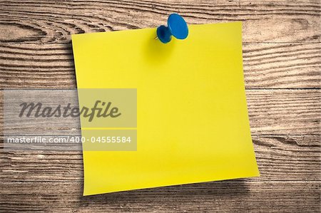 Yellow paper note with thumbtack on wooden surface, clipping path.