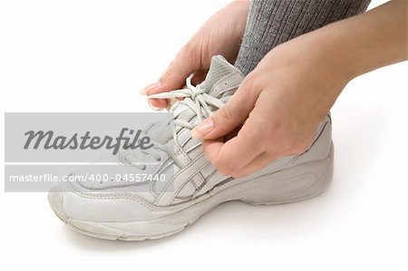 Woman tying her running shoes. White background.