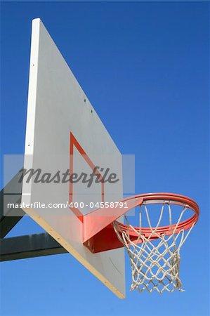 Basketball net and backboard over clear blue sky.