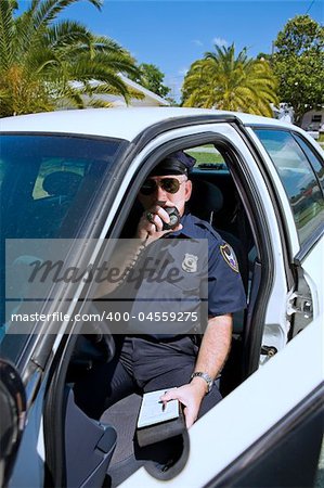 Police officer in his car calling in a license number on his radio.
