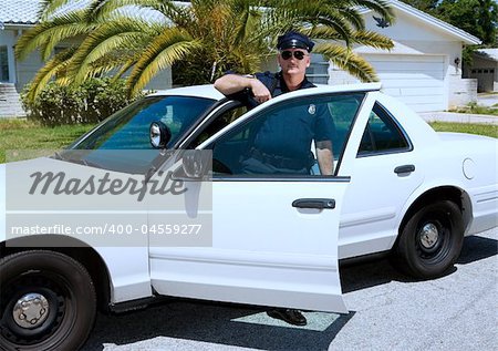 Uniformed law enforcement officer standing in the door of his police car.