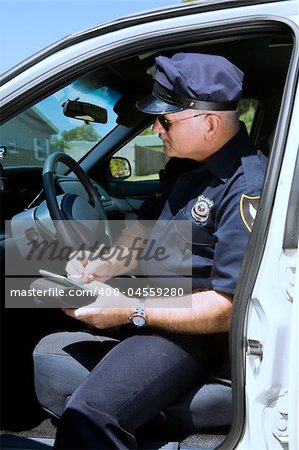 Police officer sitting in his squad car writing a citation.