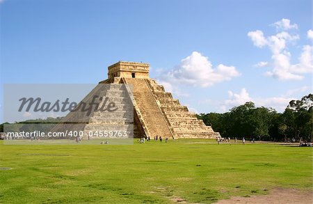 Antique mayan pyramid on green field over blue sky