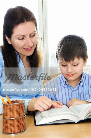 Teacher or tutor helping school boy to study