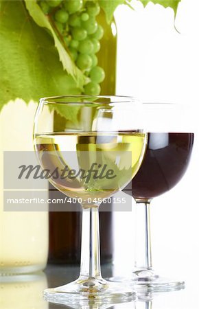 view of  wine bottle with vine and  full wineglasses  on white back