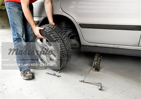 A male changing a tire on a car in a garage