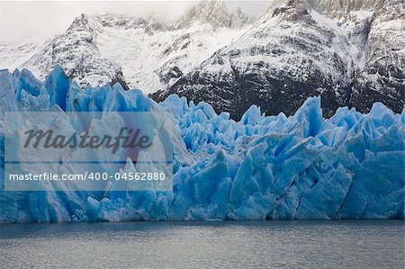 Vibrant blue icebergs in front of snowy mountains taken at Grey Glacier in Torres del Paine National Park, Patagonia.