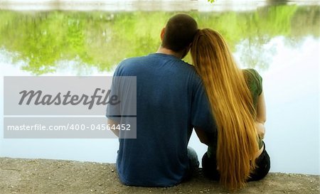Romantic couple hugging and sitting on lakeside