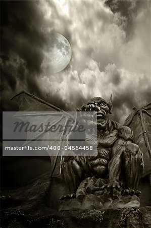 Night demon - close-up on frightening statue, with moon emerging from clouds