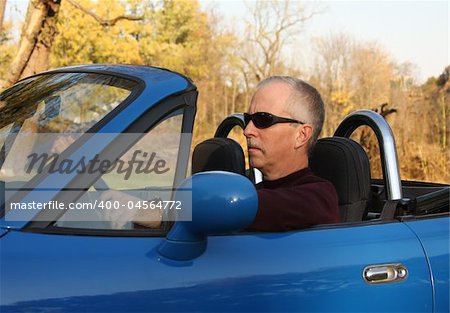 Middle-aged man in a blue convertible sports car