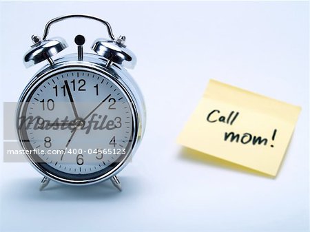 An alarm clock and a yellow note with this text 'Call mom!'