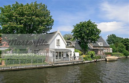 Historical houses in The Netherlands (Holland) with boat, canal and trees