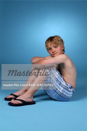 Young boy in blue plaid shorts against a blue background