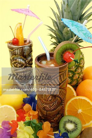 Tropical drinks served in Tiki style glasses and fruits