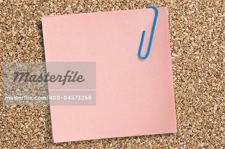 Pink paper note with clip on cork board.