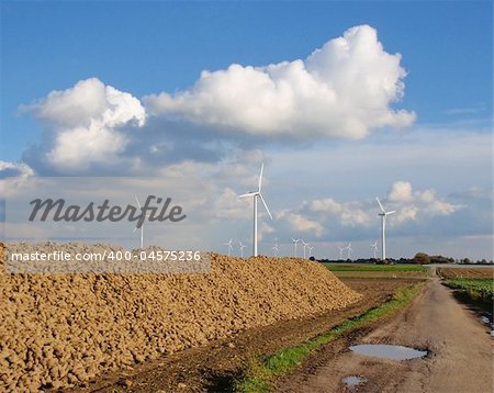 windmill park on a green meadow with blue sky with stack of sugar beet