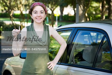 Pretty teen girl holding up the keys to her new car.