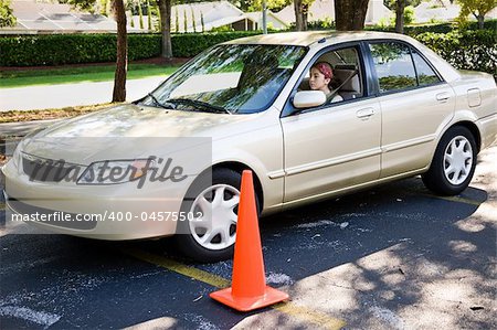 Teen girl learning to parallel park a car.