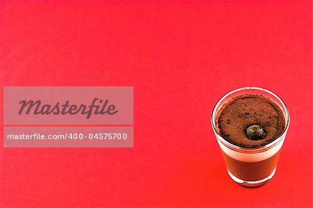 Glass of mousse a chocolat on a red background. Space left for text.