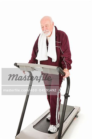 Tired senior man forcing himself to walk a treadmill to get back in shape.  Isolated on white.