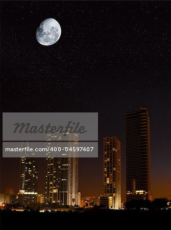 Night in the city - moon showing in the sky over skyscrapers