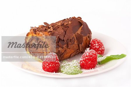 Miniature chocolate swiss roll cake served on a plate with mint leaves and raspberries on white background