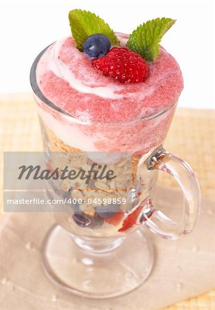 Healthy breakfast with muesli, raspberries, blueberries and yoghurt, decorated with mint leaves in a glass