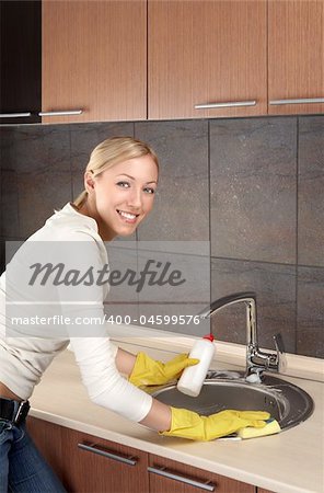 The smiling blonde washes ware in a bowl on kitchen