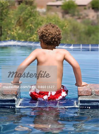 Young boy sitting on the edge of a swimming pool