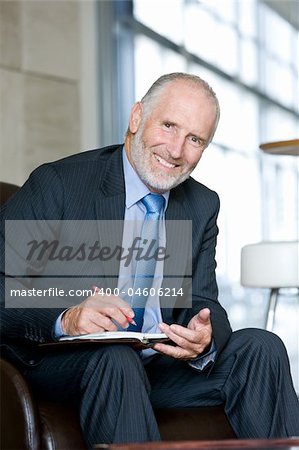 Portrait of smiling Senior business man writing on notepad