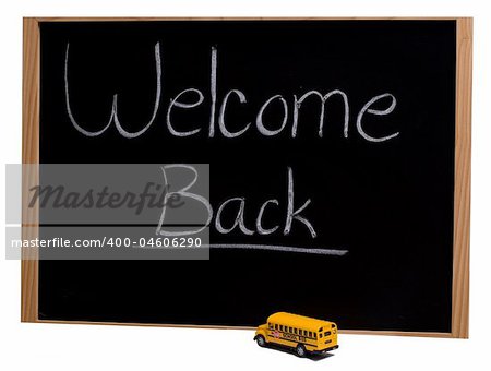 A blackboard with the words "welcome back" and a toy school bus parked in front of it