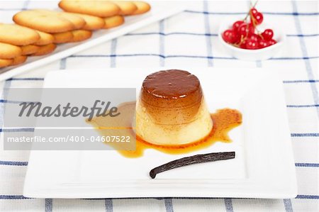 Vanilla cream caramel dessert and cookies on white dish. Shallow depth of field