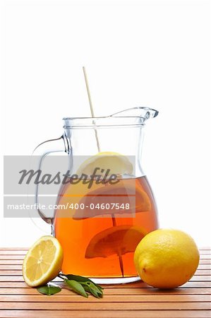 Ice tea pitcher with lemon and icecubes on wooden background