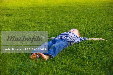 The four-year boy lies on a grass
