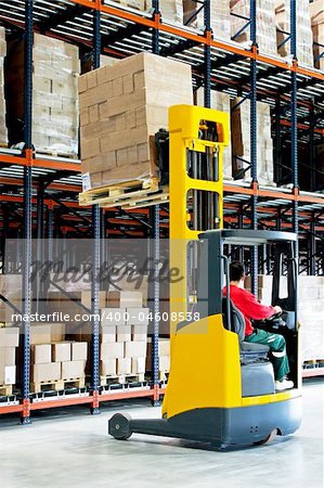 Yellow fork lifter with pallet in warehouse