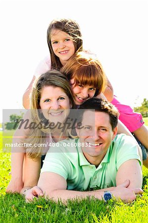Portrait of happy family of four laying on grass at the park