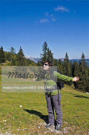 A girl who raises the arms and looking at the sky in the meadow